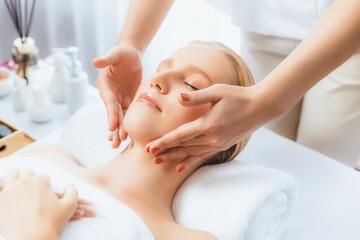Fototapeta premium Caucasian woman enjoying relaxing anti-stress head massage and pampering facial beauty skin recreation leisure in dayspa modern light ambient at luxury resort or hotel spa salon. Quiescent