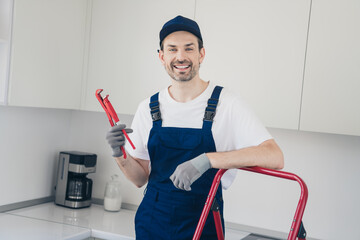 Smiling handyman standing with wrench in modern kitchen ready for renovation work and maintenance tasks