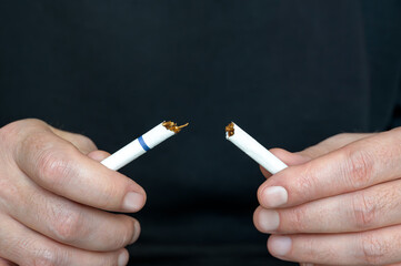 Quitting smoking and fighting bad habits. Male hands in close-up breaking a cigarette
