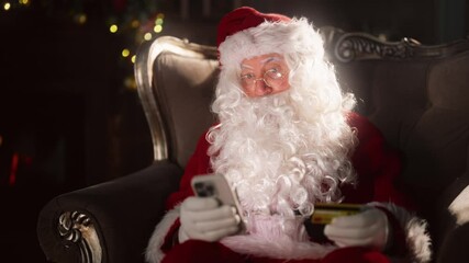 Curious Santa Claus using modern technology, pay by credit card in smartphone. Portrait of emotional old wizard with beard holding mobile phone and shopping online, internet fraud, cyber security