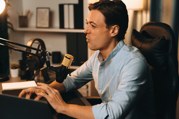 Host channel smart broadcaster talking on live social media application searching on laptop, broadcasting streamer wearing headphone using mic at modern home office studio in warm lighting. Pecuniary.