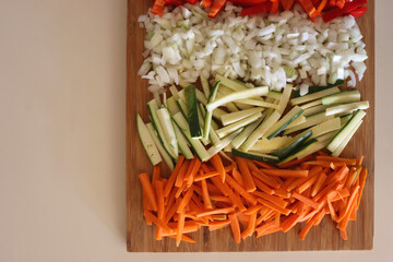 Chopped leek, red pepper, onion, zucchini and carrot on the chopping board. Cooking and meal prepping at home. Flat lay.