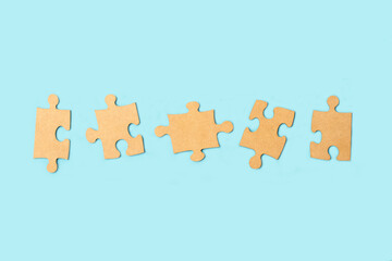 Blank brown puzzle pieces on a light blue background with copy space