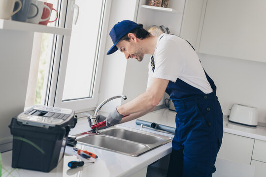 Skilled handyman performing kitchen sink repair with focus and precision in modern home environment