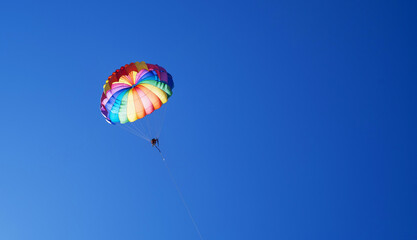 Tourists fly on a bright paraglider against the blue sky in the summer on a sunny day. Beach holidays, tourist marine entertainment. Parasailing