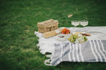 Cozy summer picnic on green meadow with fresh fruits, cheese and cold champagne.