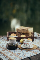 Cozy picnic with hot tea and cookies near lake.