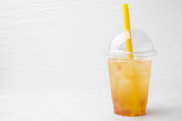 Tasty bubble tea in plastic cup on white tiled table against light background, space for text