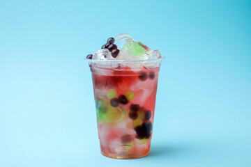 Tasty bubble tea in plastic cup on light blue background
