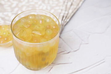 Tasty bubble tea in glass and tapioca pearls on white table, closeup. Space for text