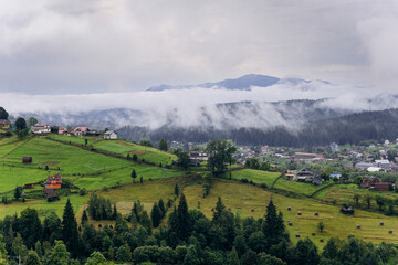 Obraz premium Misty morning in Vorokhta village with scenic view of Carpathian hills and fog-covered mountains