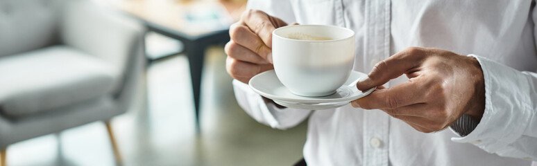 A diligent businessman dressed in a white shirt enjoys coffee while working on innovative project...