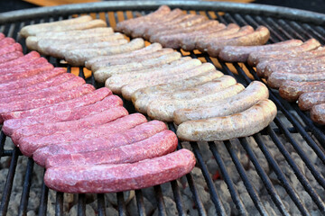 Close-up of large sausages with different meats on an open grill outside. Delicious food for a large group of people.