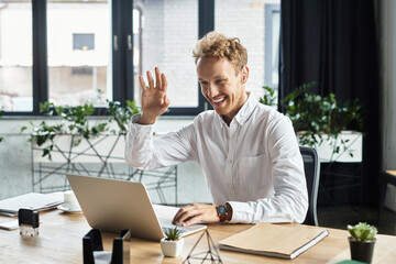 A redhead businessman in a white shirt joyfully engages in a work project while seated at a sleek desk.