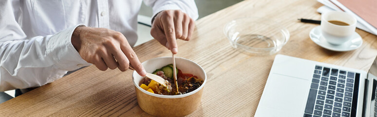 A businessman in a white shirt enjoys a nutritious lunch while concentrating on his project work.