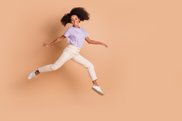 Full length portrait of pretty young woman jump empty space wear t-shirt isolated on beige color background