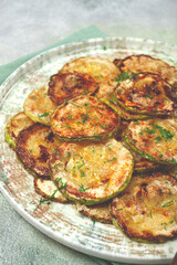 fried zucchini, cut into rings, with garlic and herbs, on a plate, top view, homemade, no people,