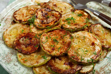 fried zucchini, cut into rings, with garlic and herbs, on a plate, top view, homemade, no people,
