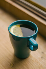 Freshly brewed tea with lemon in blue cup on wood windowsill . High quality photo