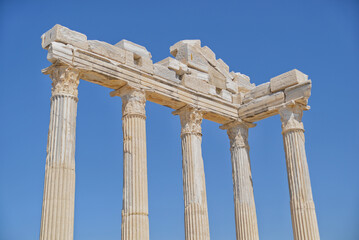 Obraz premium Roman ruins of an ancient city. Columns of a ruined temple of Apollo at the background of sky. Archaeology excavation of Side, Turkey