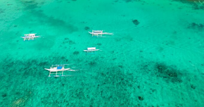 Drone view following the boats running over turquoise sea water. Boracay, Philippines.
