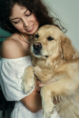 Portrait of a happy young woman and her dog sitting together at home. Golden retriever and owner