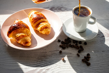 breakfast with coffee and croissant on white wooden background