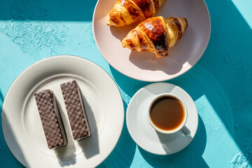breakfast with coffee and croissant on blue background