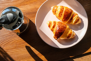 breakfast with coffee and croissant on wooden background