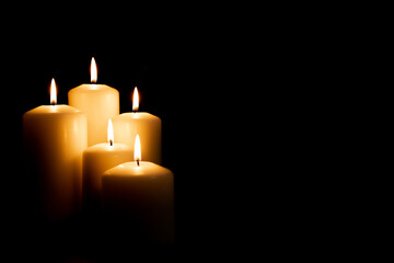 Burning white candles on a black background. Front view.