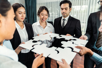 Multiethnic business people holding jigsaw pieces and merge them together as effective solution...