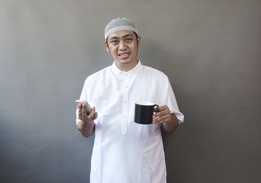 Smiling Muslim Man with Smartphone and Coffee Mug