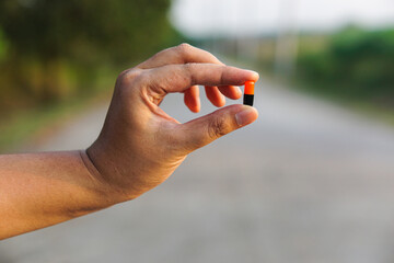 Close-up of a Hand Holding a Single Capsule Pill Outdoors