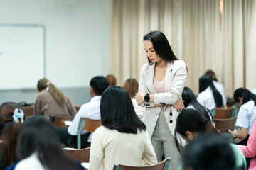 A teacher carefully monitors students taking an exam in a classroom, ensuring focus and discipline during academic assessment.