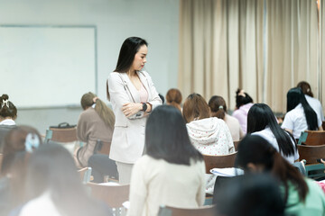 A teacher carefully monitors students taking an exam in a classroom, ensuring focus and discipline...