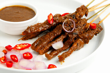 Chicken satay dish with peanut sauce, chili, and chopped onion isolated in white plate and background