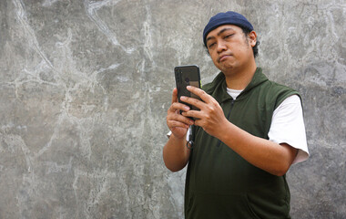 Man using smartphone against textured wall background