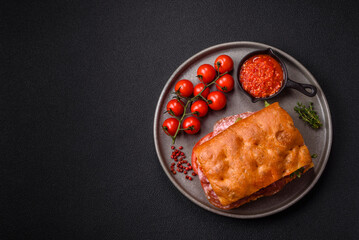 Focaccia with salami, cheese, tomatoes, arugula, salt, spices and herbs