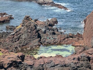 A rocky shoreline with a small water pool in the middle