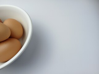 Group of brown raw eggs on a bowl, with copy space for text  isolated on white background