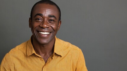 Fototapeta premium Radiant smile illuminates a portrait of a charismatic man in a vibrant yellow shirt, exuding warmth and positivity against a neutral backdrop. Joy personified.