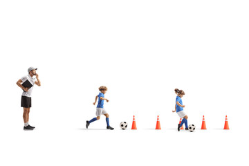 Coach training a boy and girl to lead a football between obstacle cones