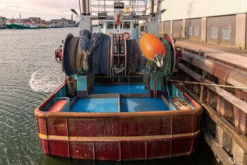 back of a moored stern trawler where the reels of fishing nets and fender buoy are clearly visible