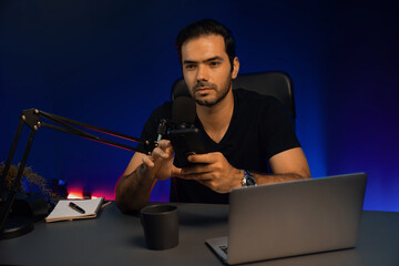 Broadcaster talking to listener on live streaming online, checking message from smartphone on...