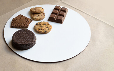 Golosinas argentinas, alfajor cubierto, galletitas y barra de chocolate sobre base blanca redonda para pedido a domicilio 