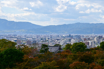 Obraz premium The view of Kyoto city skyline with blue sky and trees from kiyomizu-dera temple in Kyoto, Japan. Major tourist attraction in Kansai region in Japan. Travel concept. Japan cityscape.
