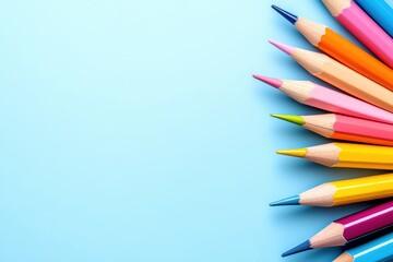 Fototapeta premium Colored pencils lined up on a blue background for creative designs.