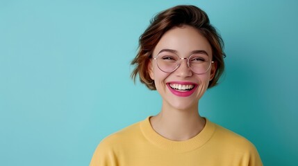 Cheerful young woman in glasses smiles brightly against a blue background.