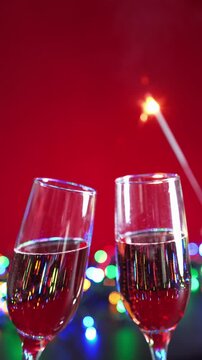 Calici di champagne con luci colorate in secondo piano e stellina che scintilla, video verticale