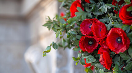 Naklejka premium A close-up of a memorial wreath, with vibrant red poppies and green leaves, resting against a white marble monument.